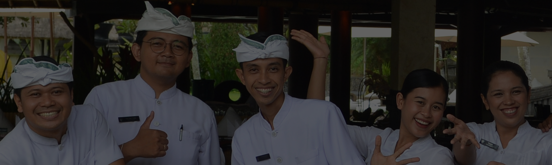 The smiling team of CasCades Restaurant, dressed in traditional white uniforms and headdresses, posing together.